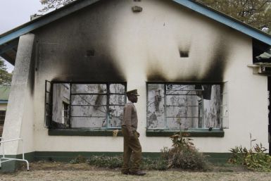 A Zimbabwean policeman walks past the burnt out home of retired army general Solomon Mujuru in Beatrice Farm