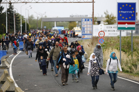 Migrants walk as they cross the border from Hungary