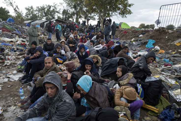 Migrants sit along a road
