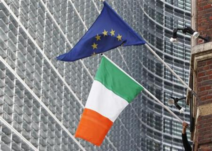 A man adjusts an Irish flag as it flies next to a European Union flag