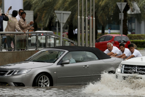 People in Dubai push car through flood