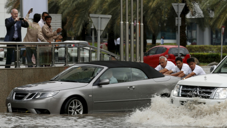 People in Dubai push car through flood