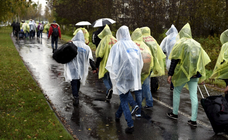 Refugees walk through the pouring rain from a public transport centre to the Lappia-building refugee reception centre in Tornio, northwestern Finland,