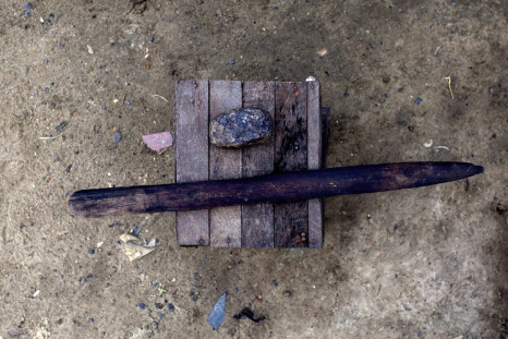 A stone and stick used for breast ironing seen on a stool outside in Douala, Cameroon