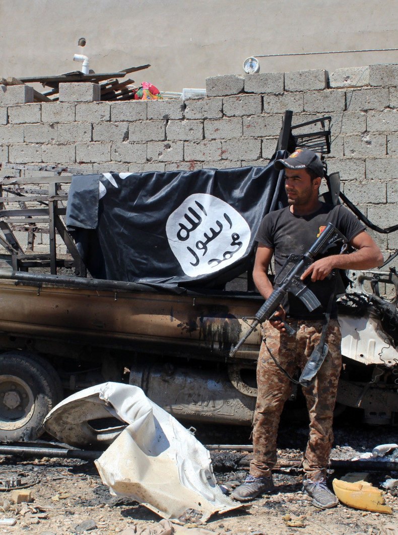 A member of Iraqi government forces inspects a burnt vehicle with on its top a flag of the Islamic State group (IS) after they retook an area from its jihadists on April 2