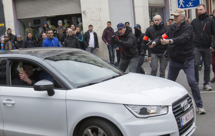 Belgian police point their guns at a car driving towards a police road block before it hit and injured a woman on the street in the Brussels district of Molenbeek,