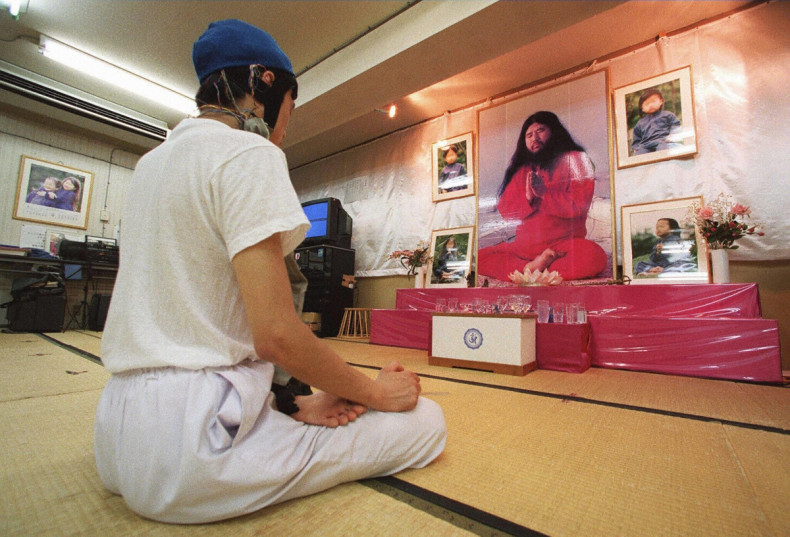 a follower meditating before portraits of Aum Supreme Truth guru Shoko Asahara