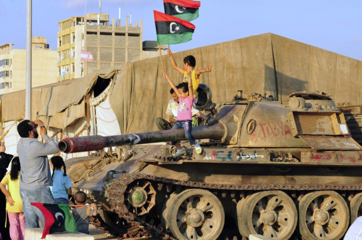 Libyan children sit on a tank while waving Kingdom of Libya flags near the court house in Benghazi