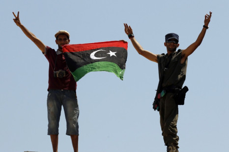 Rebel fighters show victory signs as they hold a Kingdom of Libya flag at the Tunisan border post of Ras Jdir