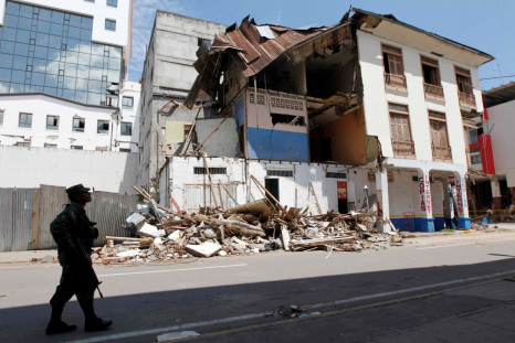 A military member walks in front of a damaged structure