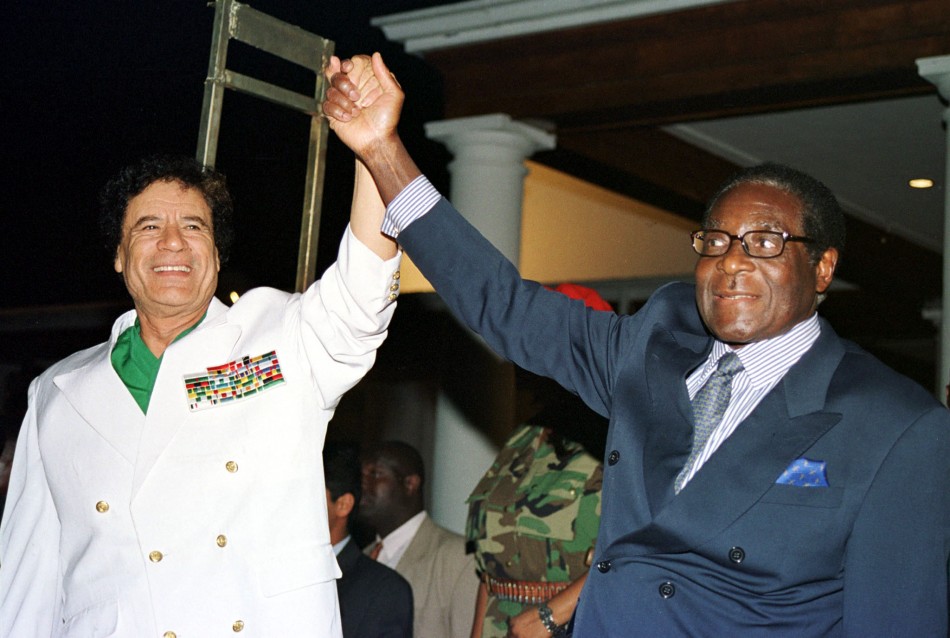 Libyan leader Colonel Muammar Gadaffi L and Zimbabwe President Robert Mugabe greet supporters outside State House in Harare July 12, 2001.