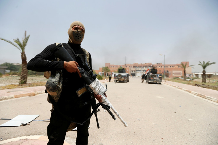 Iraqi security forces walk with their weapons at Fallujah hospital