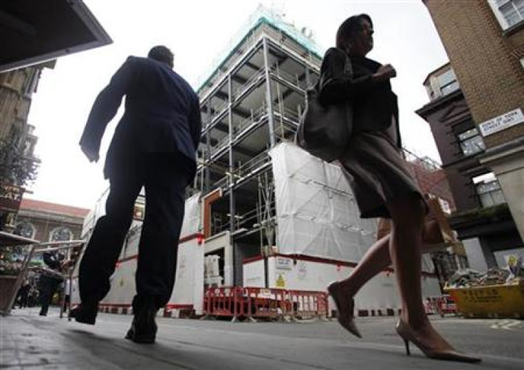 Pedestians walk past a building under construction in central London