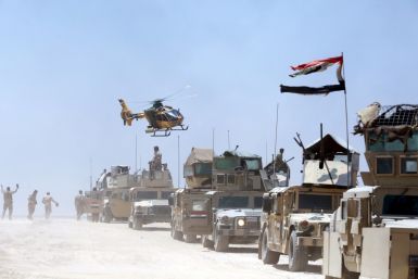 An Iraqi helicopter flies over military vehicles in Husaybah, in Anbar province