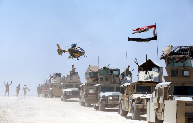 An Iraqi helicopter flies over military vehicles in Husaybah, in Anbar province