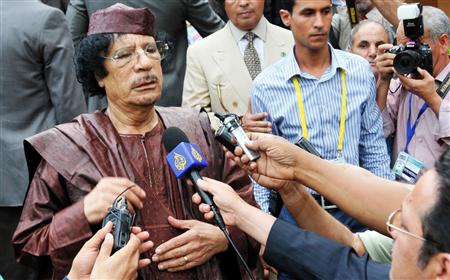 Libyan leader Gaddafi addresses the media as he leaves the venue of the AU Summit in Kampala