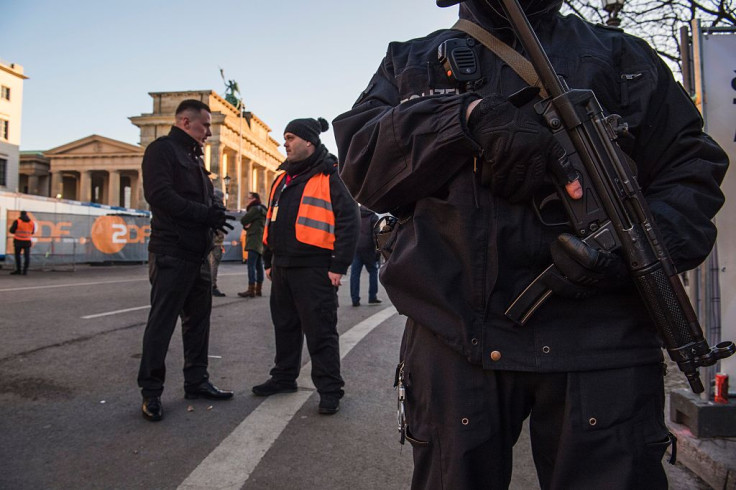 A police officer (R) and security guards (L) stand guard near the capital's Brandenburg Gate on December 31, 2016,