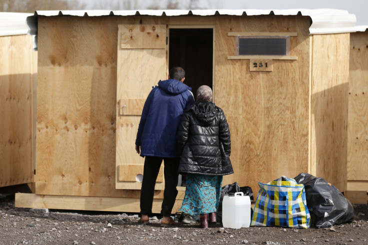 Kurdish migrant family stands at the door of their wood shelter in a refugee camp in Grande-Synthe, near Dunkirk