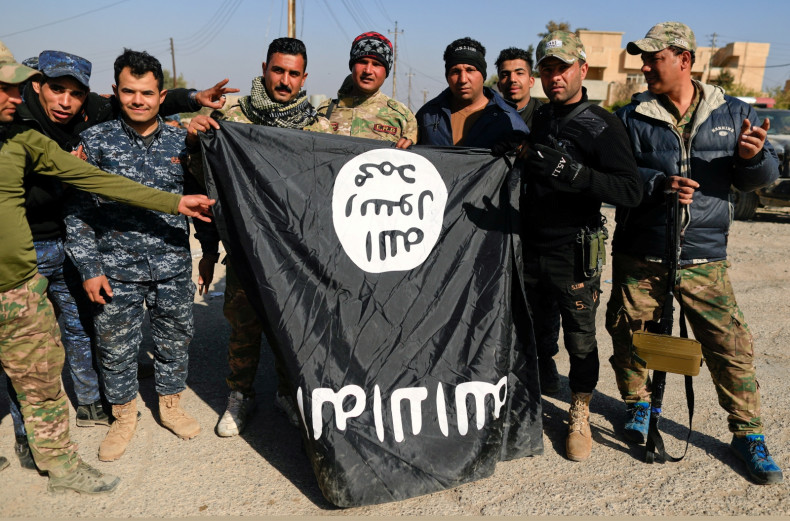 Iraqi security forces members pose with a seized Islamic State flag after driving out its miitants from Mosul's airport south west Mosul