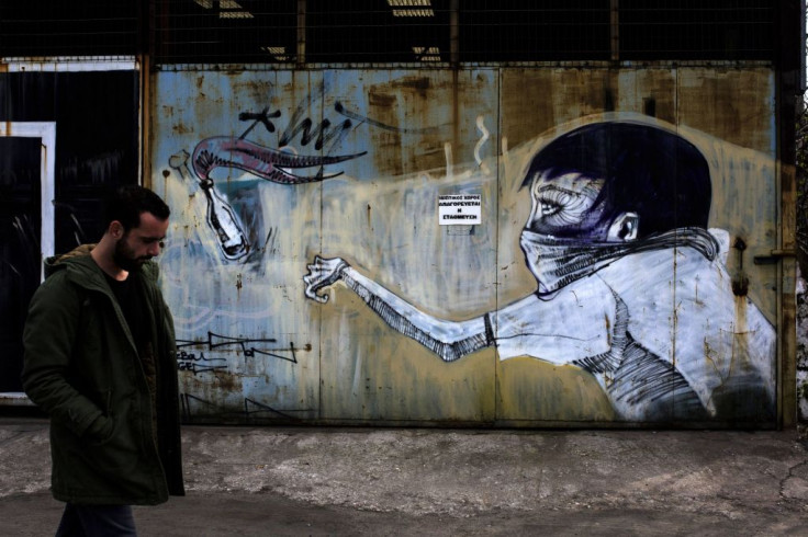 A man walks past a graffiti depicting a man throwing a petrol bomb