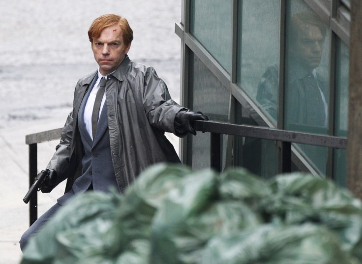 Actor Hugo Weaving crouches as he holds a gun during filming of "Cloud Atlas" in Glasgow, Scotland