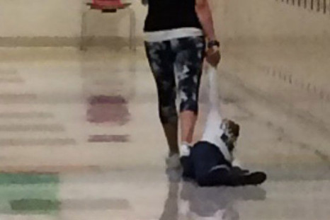 A teacher dragging a young student by the arm 