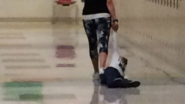 A teacher dragging a young student by the arm