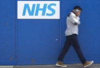 Man walking past NHS sign