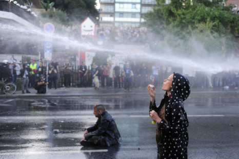Protester blows bubbles under water cannon