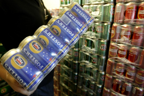 A customer carries Fosters beer cans from the cool room at a liquor store in Melbourne