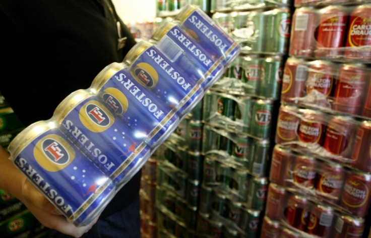 A customer carries Fosters beer cans from the cool room at a liquor store in Melbourne