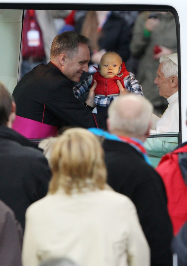A baby boy is lifted into the Popemobile to meet Pope Benedict XVI as the pontiff arrives to conduct a Holy Eucharist at the Olympic stadium in Berlin