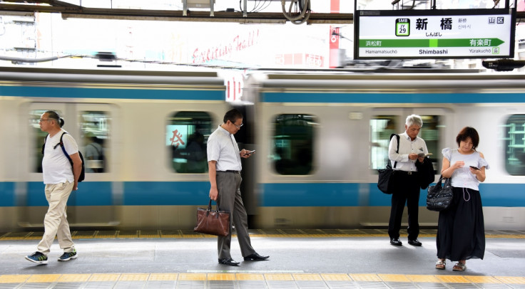 People using smartphones on Japanese train platform
