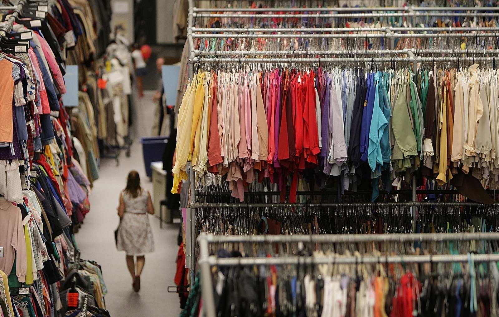 A woman walks between racks of clothes