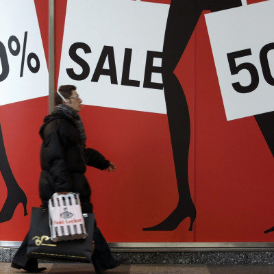 Man walks past sale shopping signs