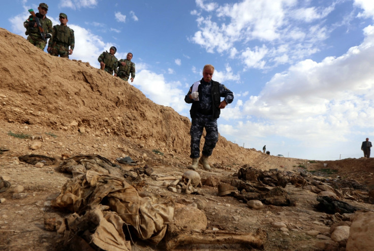 Kurdish forces look at the remains of Yazidis killed by the Isis jihadist group 