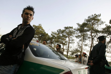 A youth leans against a police car after being detained for a Western-style haircut in Tehran
