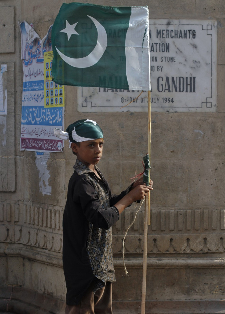 A boy ties up a Pakistan national flag to a bamboo stick as some of nearly a dozen traders near by taking part in an anti-American demonstration in Karachi A boy ties up a Pakistan national flag to a bamboo stick as some of nearly a dozen traders near by taking part in an anti-American demonstration in Karachi