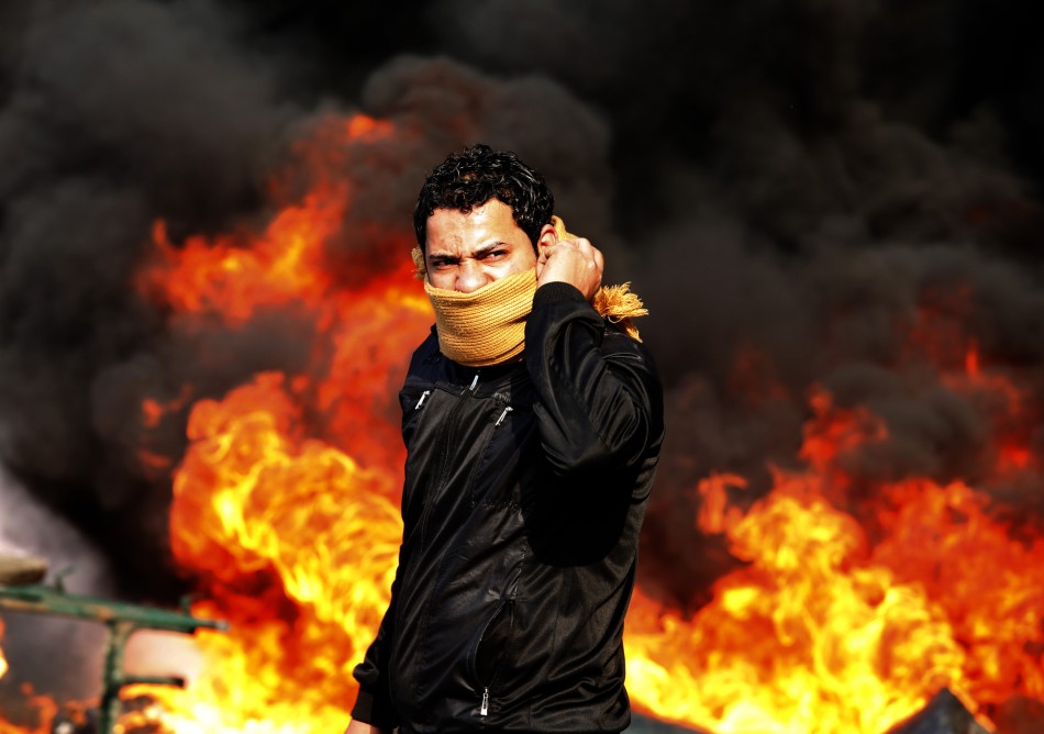 A protester stands in front of a burning barricade during a demonstration in Cairo