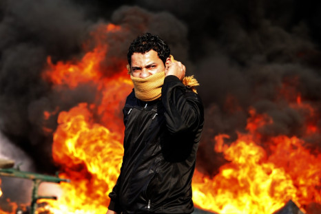 A protester stands in front of a burning barricade during a demonstration in Cairo