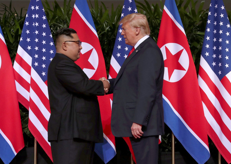 Donald Trump shakes hands with Kim Jong Un