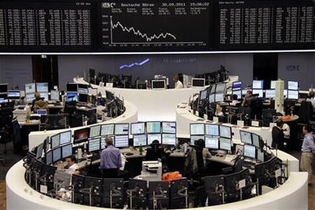 Traders work at their desks in front of the DAX board at the Frankfurt stock exchange