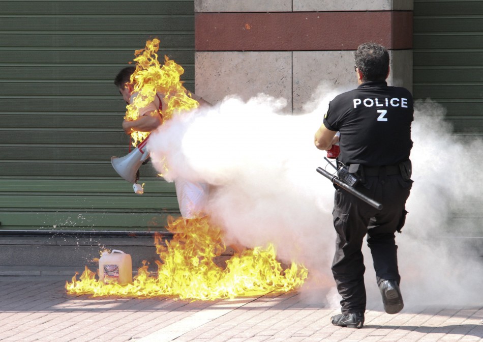 A policeman tries to extinguish a fire on a man after set himself ablaze outside a bank branch in Thessaloniki in northern Greece