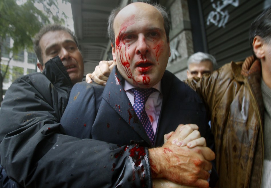 Former conservative minister Kostis Hatzidakis is covered with blood in central Athens