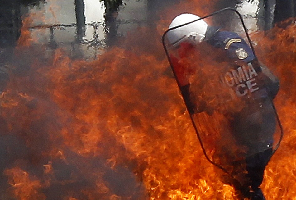 Policemen try to escape a fire from a petrol bomb during riots at May Day rally in Athens