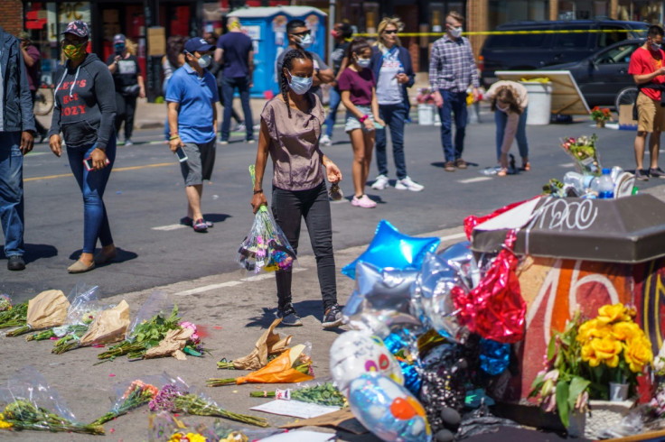 A woman brings flowers to a memorial for George Floyd