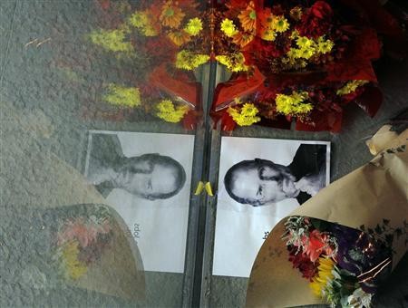 Flowers and a photograph of Steve Jobs are placed against the window outside an Apple store in Boston, Massachusetts