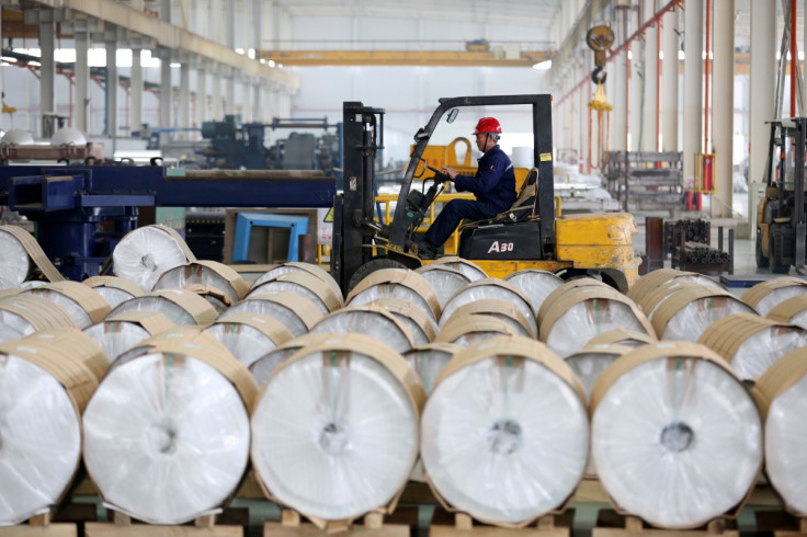 Worker drives a forklift past aluminum rolls at a factory in Huaibei, Anhui