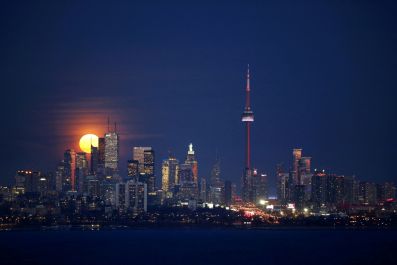 The moon rises behind the skyline and financial district in Toronto