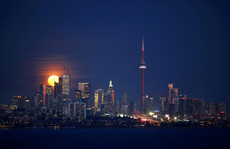 The moon rises behind the skyline and financial district in Toronto